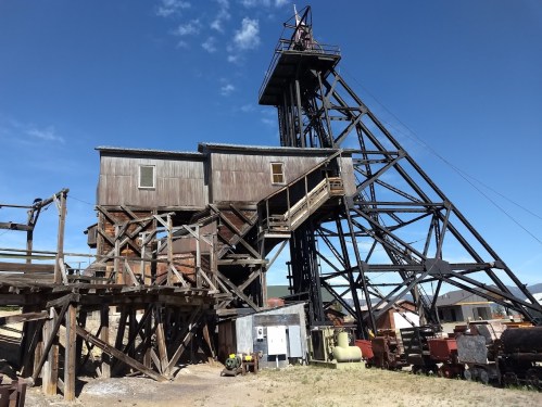 Historic mining structure with wooden and metal elements, set against a clear blue sky.