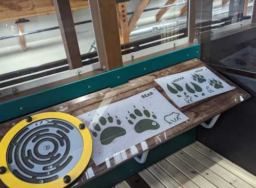 Interactive display showing animal tracks, including bear, moose, and wolf, in a nature center setting.