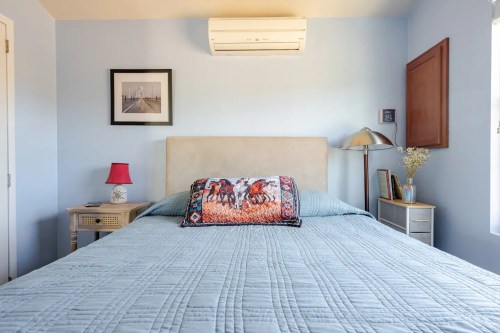 Cozy bedroom with a blue wall, a bed with a decorative pillow, a lamp, and a framed photo on the wall.
