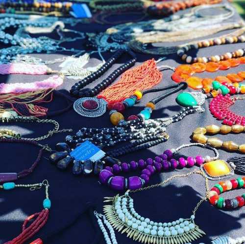 A variety of colorful necklaces displayed on a black tablecloth, showcasing different styles and materials.