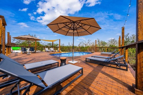 outdoor wooden deck with pool, lounge chairs, and giant umbrella