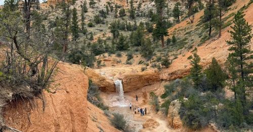 People standing around Tropic Ditch Falls in Utah