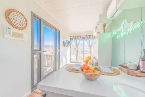 a white counter with fruits and plates in the kitchen with floor to ceiling windows in new mexico