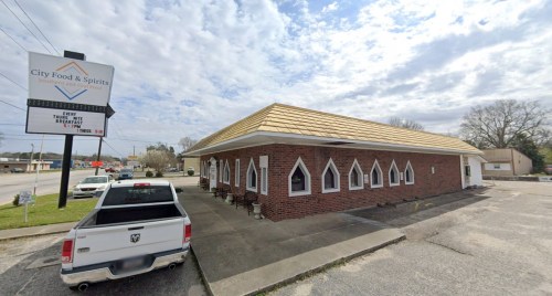 A brick building with a golden roof, featuring arched windows and a sign for "City Food & Spirits."