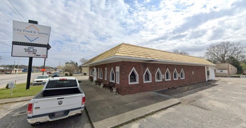 Exterior view of City Food & Spirits, featuring a brick building with a distinctive gold roof and arched windows.