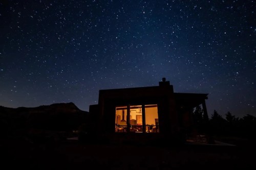 A cozy cabin illuminated from within, set against a starry night sky.