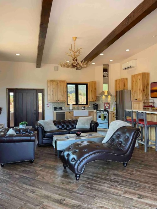 Cozy living area with leather furniture, wooden accents, and a modern kitchen in a bright, open space.