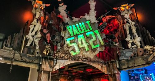 A decorative entrance sign for 'Vault 5421' a speakeasy in Orlando, FL, featuring rustic wood, chains, and various props.