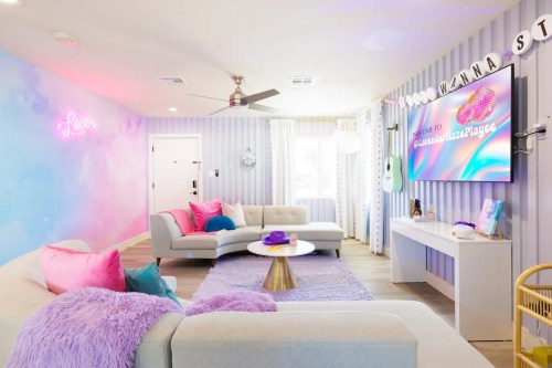 Bright, modern living room with pastel colors, plush pillows, a large TV, and a cozy atmosphere.