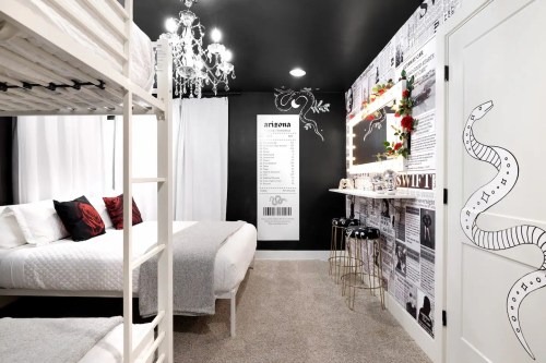 A stylish bedroom featuring a bunk bed, a double bed, a chandelier, and a wall decorated with newspaper clippings.