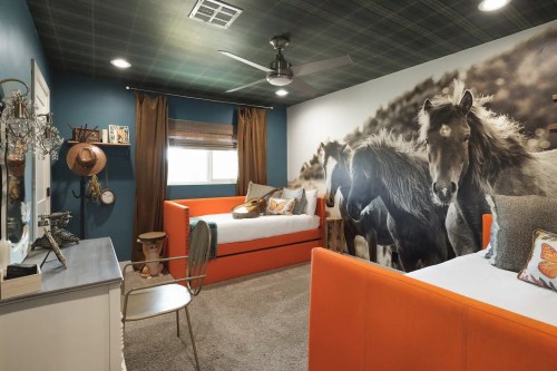 A cozy bedroom featuring orange beds, a horse mural, and rustic decor with a fan and warm lighting.
