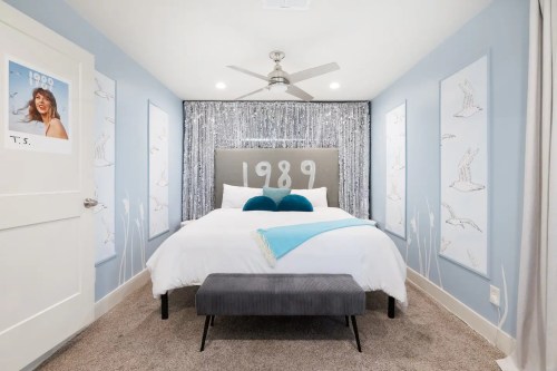 A cozy bedroom featuring a large bed, decorative wall art, and a shimmering backdrop with the year "1989."