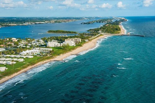 Aerial view of a coastal landscape featuring sandy beaches, lush greenery, and blue waters under a clear sky.