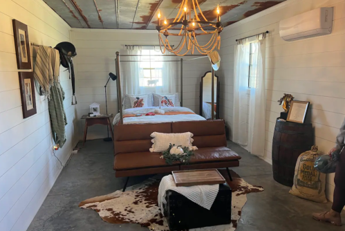 Cozy bedroom with a four-poster bed, rustic decor, chandelier, and a mix of modern and vintage furnishings.