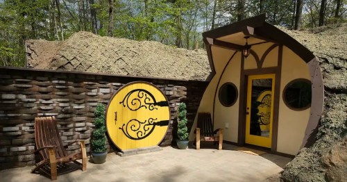 Whimsical earth-sheltered home with a round yellow door and unique curved architecture.