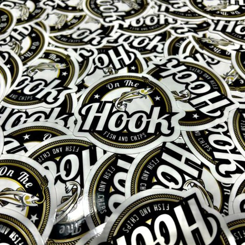 A close-up of multiple circular stickers featuring the logo for "On The Hook Fish and Chips."