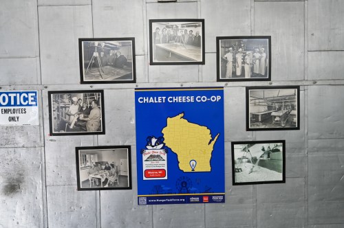 A wall display featuring historical black-and-white photos and a colorful poster for Chalet Cheese Co-Op in Wisconsin.