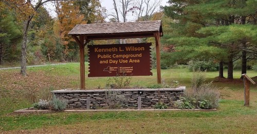 Sign for Kenneth L. Wilson Public Campground and Day Use Area, surrounded by trees and greenery.
