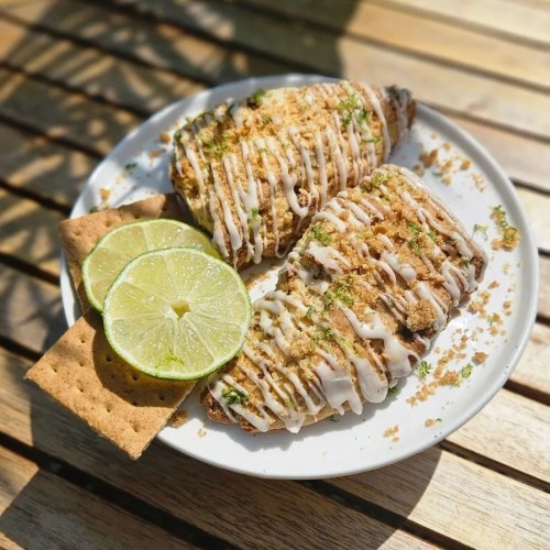 A plate with two dessert pastries drizzled with icing, garnished with lime slices and graham crackers.