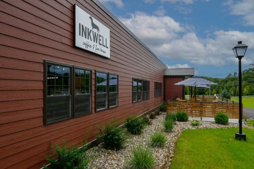 Exterior view of Inkwell Coffee & Tea House, featuring a brown wooden building, patio, and landscaped garden.