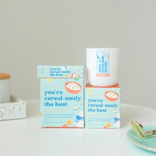 A candle and box with colorful cereal-themed design, labeled "you're cereal-ously the best" in a bright, playful style.