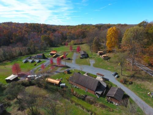 Aerial view of a scenic rural area with colorful autumn trees, cabins, and a winding road.