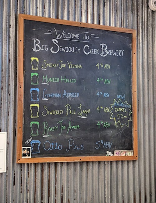 Chalkboard menu at Big Sewickley Creek Brewery listing various beers and their ABV percentages.