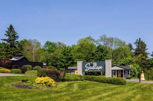 A scenic view of Seascape Hotel & Cottages sign surrounded by lush greenery and colorful landscaping on a sunny day.