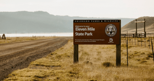 Sign welcoming visitors to Eleven Mile State Park, with a scenic landscape in the background.