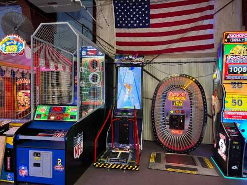 A colorful arcade with various games, including a basketball shooter and a Monopoly game, against an American flag backdrop.