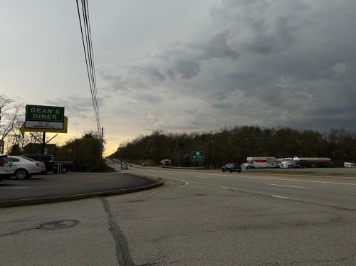 A roadside view of Dean's Diner sign with cloudy skies and vehicles on a highway.