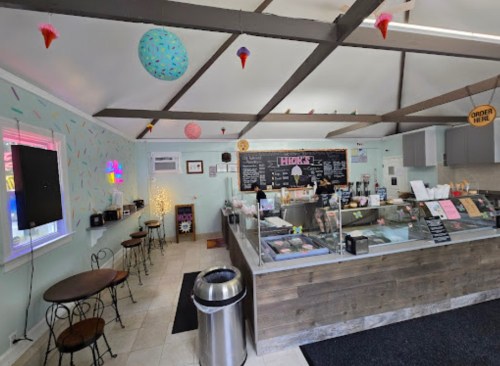 Bright ice cream shop interior with a service counter, tables, colorful decor, and a chalkboard menu.