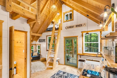 Cozy wooden cabin interior with a loft, large windows, and a warm, inviting atmosphere.
