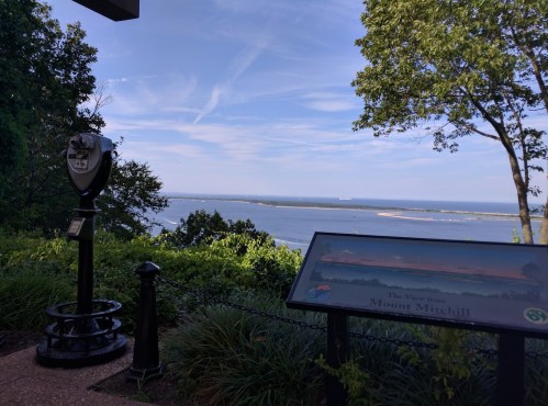 View from Mount Mitchell featuring a scenic landscape, a viewing telescope, and an informational sign.