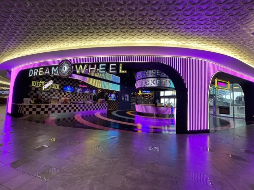 A vibrant arcade entrance with neon lights and a colorful design, featuring the "Dream Wheel" sign.