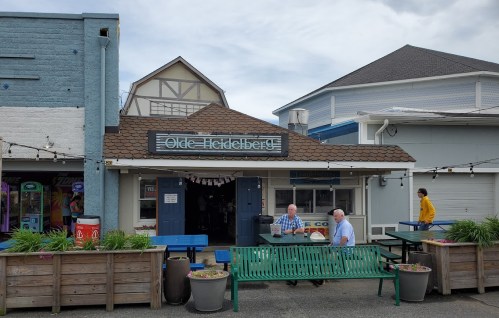 A quaint building with a sign reading "Olde Heidelberg," featuring outdoor seating and people dining.