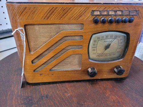 Vintage wooden radio with a dial and knobs, featuring a retro design and fabric speaker cover.