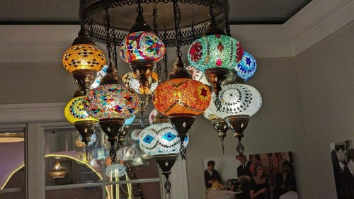 A colorful chandelier with intricately designed glass lamps hanging from a decorative metal frame.