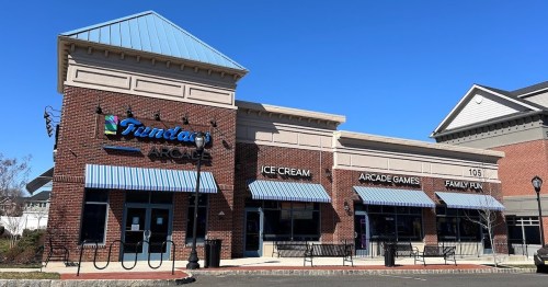 Exterior of a family entertainment center featuring ice cream, arcade games, and family fun activities under a clear blue sky.