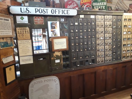 Interior of a vintage U.S. Post Office with wooden counters, mailboxes, and nostalgic signage.
