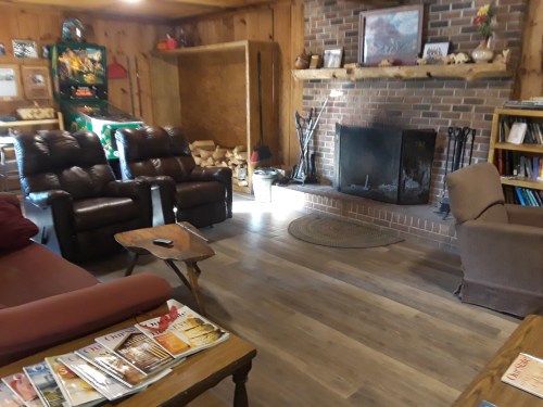 Cozy living room with leather recliners, a brick fireplace, wooden shelves, and a rustic decor.