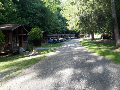 A gravel road lined with cabins and trees, creating a serene, wooded atmosphere.