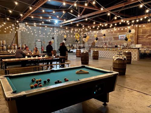 A spacious venue with a pool table, string lights, and a birthday celebration setup featuring barrels and decorations.