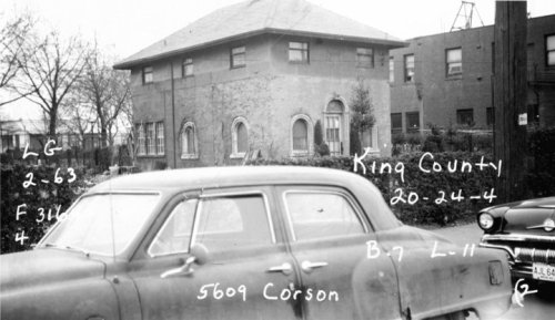 Black and white photo of a building with arched windows, a parked car in front, and handwritten notes on the image.