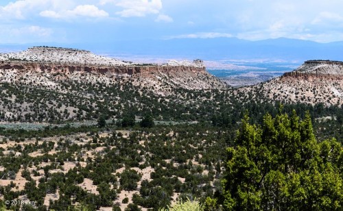 A panoramic view of rugged cliffs and green vegetation under a cloudy sky in a mountainous landscape.