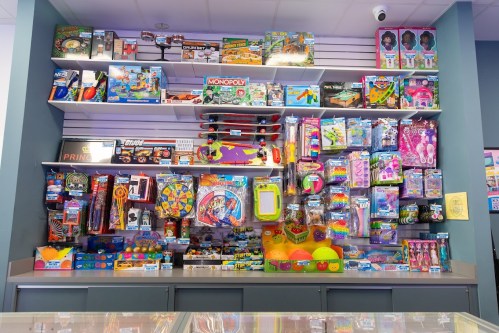A colorful display of various toys and games on shelves in a store, including board games, action figures, and craft kits.