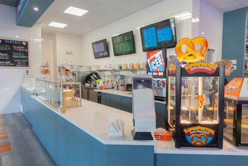 A bright snack counter featuring a pretzel display, drink machines, and menu boards in a modern setting.