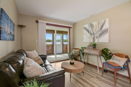 Cozy living room with a brown sofa, round coffee table, and plants, featuring a sliding door to a scenic outdoor view.