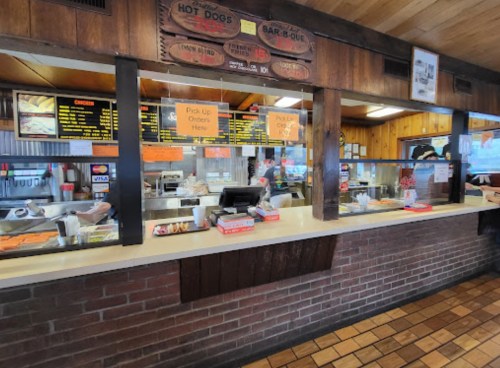 A fast-food counter with a menu, order pick-up signs, and a variety of food items displayed behind the glass.