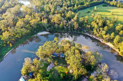 Aerial view of a river winding through lush greenery, with small houses nestled along the banks.